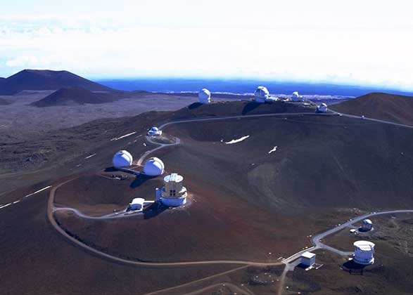 НА ВЕРШИНЕ МАУНА-КЕА, древнего вулкана на Гавайях, расположились десятки телескопов. Астрономов привлекает сюда большая высота и очень сухой чистый воздух. Внизу справа сквозь открытую щель башни хорошо видно зеркало телескопа «Кек I», а внизу слева – строящуюся башню телескопа «Кек II».