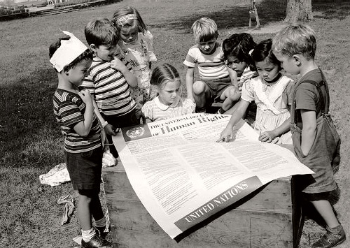 Дети из Международного дошкольного учреждения ООН в Нью-Йорке рассматривают плакат со Всеобщей декларацией прав человека во второю годовщину её принятия. 1950 год. Фото ООН. www.un.org